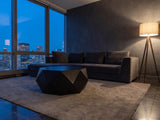 Taranto Black Faceted Drum Coffee Table on a wool rug in front of a velvet sofa in a city penthouse at blue hour