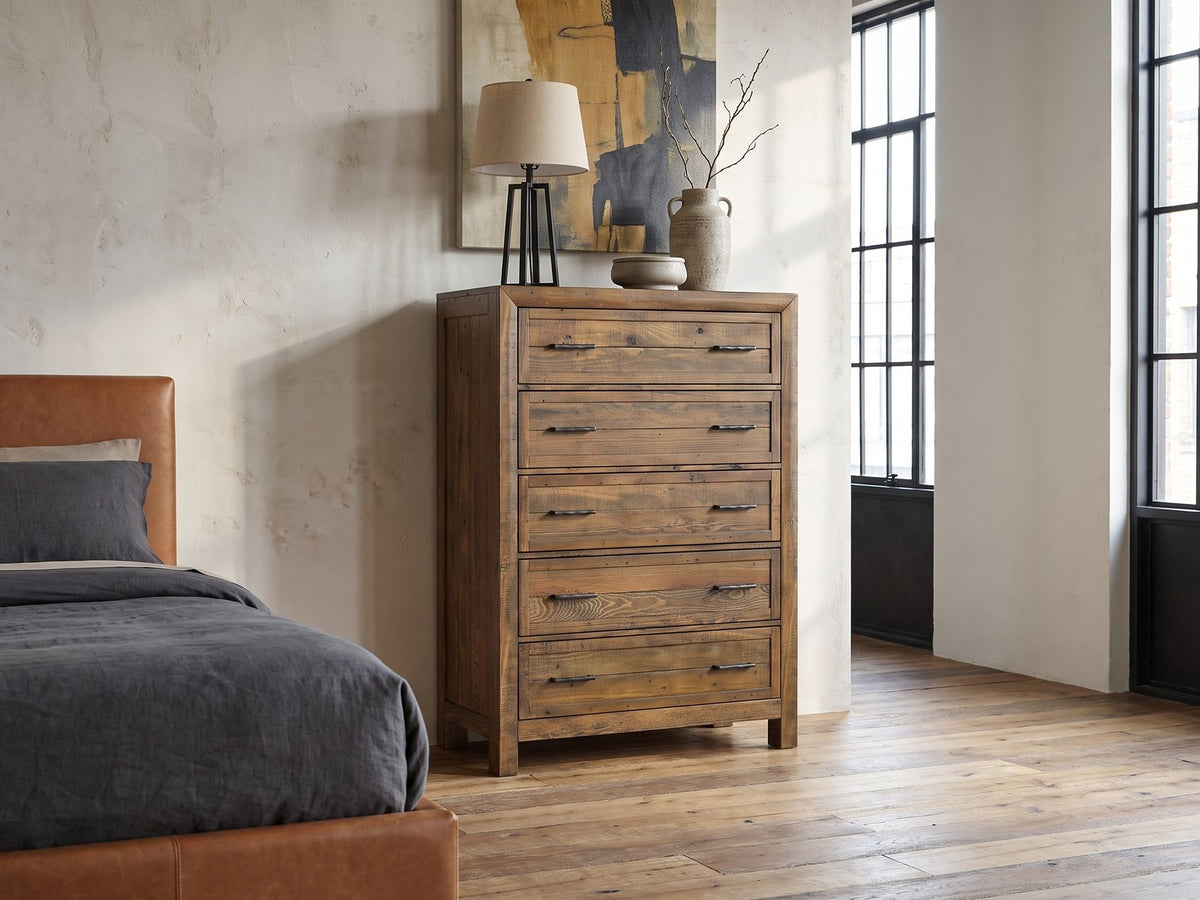 Tarvisio 37-Inch Rustic Caramel 5-Drawer Chest against a plaster wall in an industrial loft bedroom