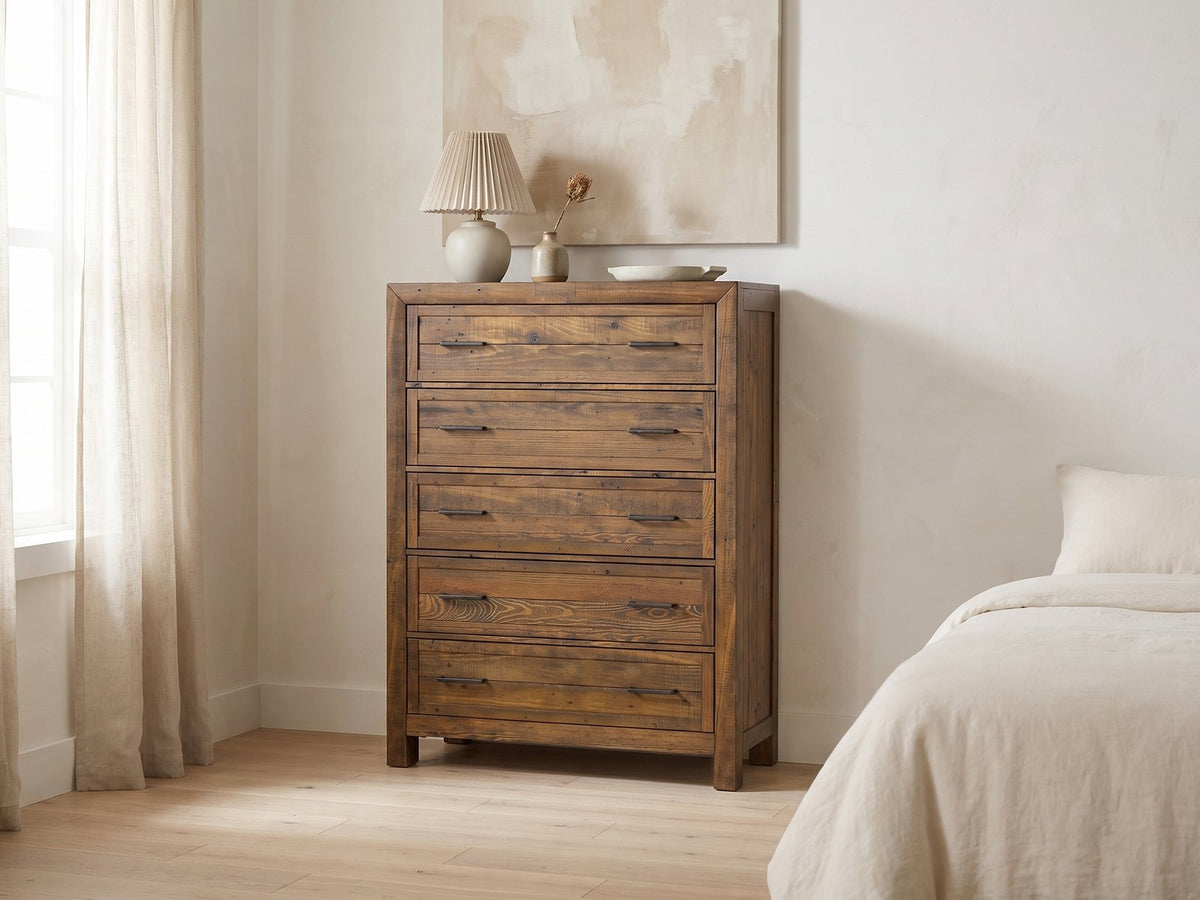 Tarvisio 37-Inch Rustic Caramel 5-Drawer Chest against a plaster wall under an abstract canvas in a bright bedroom