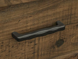 Close-up of the Tarvisio 37-Inch Rustic Caramel 5-Drawer Chest: the dark hand-forged iron pull on a rough-sawn pine drawer front