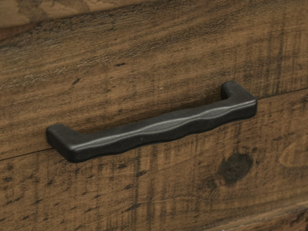Close-up of the Tarvisio 37-Inch Rustic Caramel 5-Drawer Chest: the dark hand-forged iron pull on a rough-sawn pine drawer front
