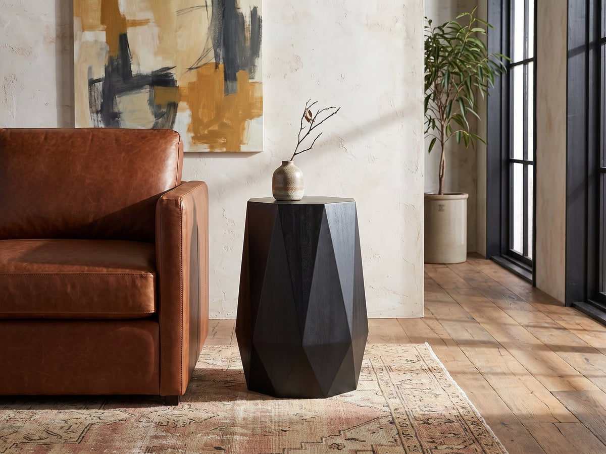Teglio Black Acacia Faceted Octagon Side Table beside a leather sofa in an industrial loft