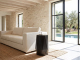 Teglio Black Acacia Faceted Octagon Side Table beside a linen sofa in a poolside villa