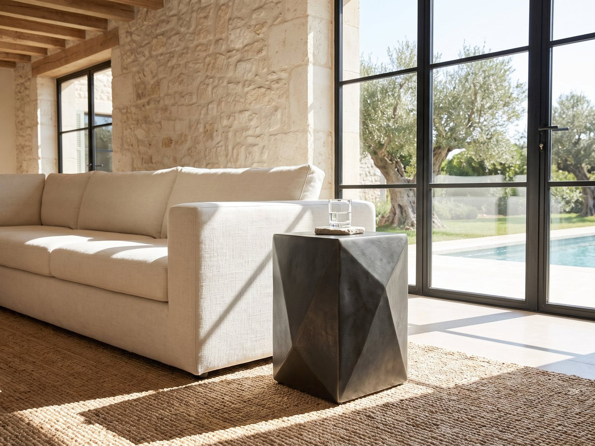 Terlizzi Graphite Cast Aluminum Faceted Side Table beside a linen sofa in a poolside villa