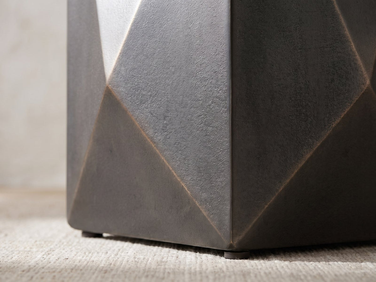 Close-up of the Terlizzi Graphite Cast Aluminum Faceted Side Table: the folded facets meeting at a lower corner above a round foot