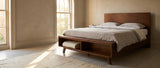 Termoli walnut platform bed in a Charleston townhouse bedroom, a tall arched window at the left and a folded blanket in the open cubby at the foot