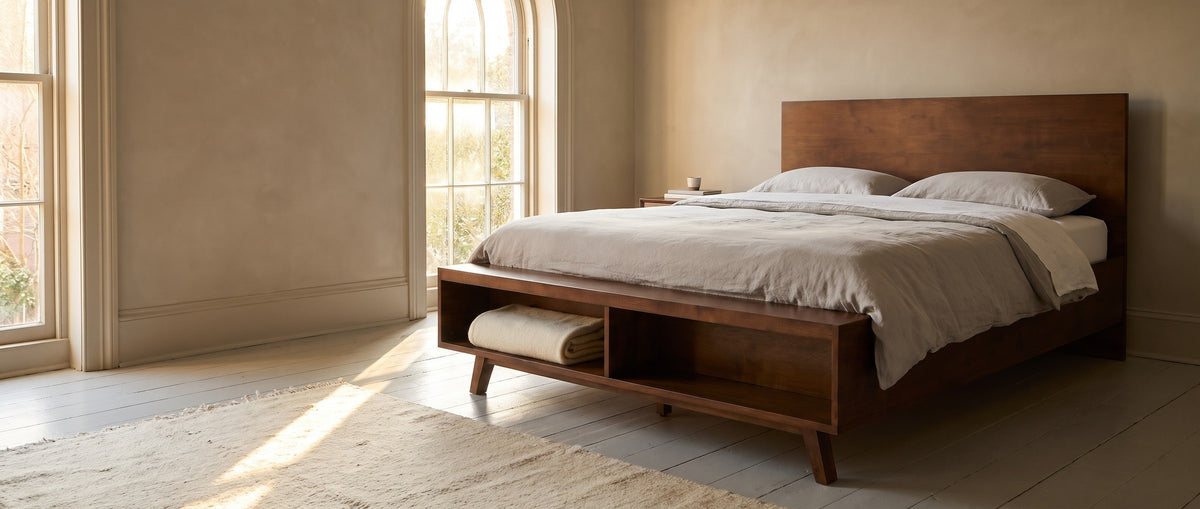 Termoli walnut platform bed in a Charleston townhouse bedroom, a tall arched window at the left and a folded blanket in the open cubby at the foot