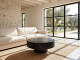 Terni Black Wood Veneer Fluted Pedestal Coffee Table on a jute rug in front of a linen sofa in a poolside villa