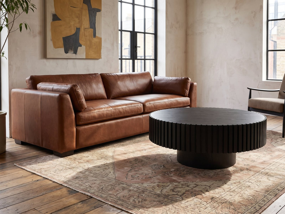 Terni Black Wood Veneer Fluted Pedestal Coffee Table on a vintage rug in front of a leather sofa in an industrial loft