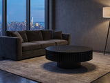 Terni Black Wood Veneer Fluted Pedestal Coffee Table on a wool rug in front of a velvet sofa in a city penthouse at blue hour