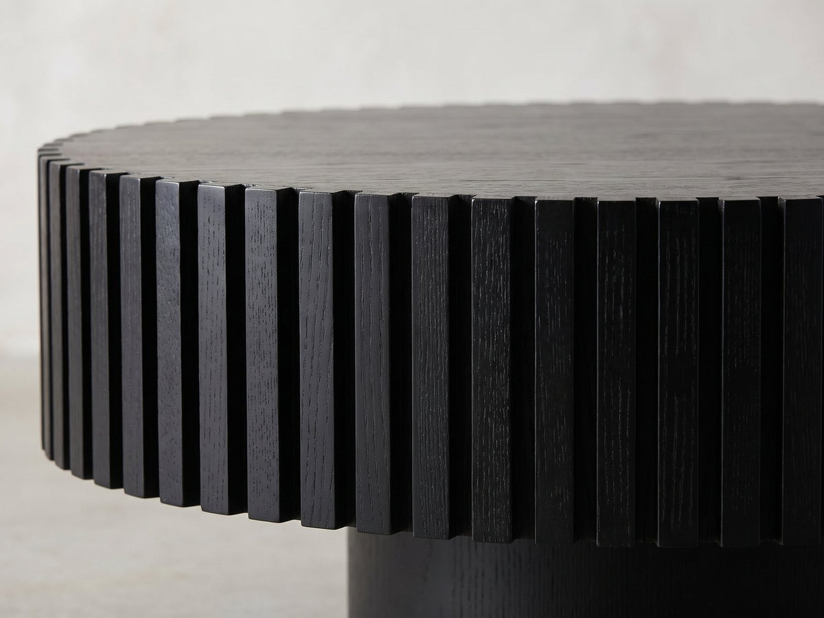 Close-up of the Terni Black Wood Veneer Fluted Pedestal Coffee Table: the black fluted slats under the notched rim of the top