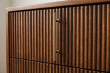 The upper drawer of the Teulada nightstand: a slim antique brass bar pull on two small posts over carved vertical reeds