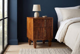 Teulada fluted mango nightstand with a ceramic lamp in a Chicago bedroom with a deep navy wall and a pale oak floor