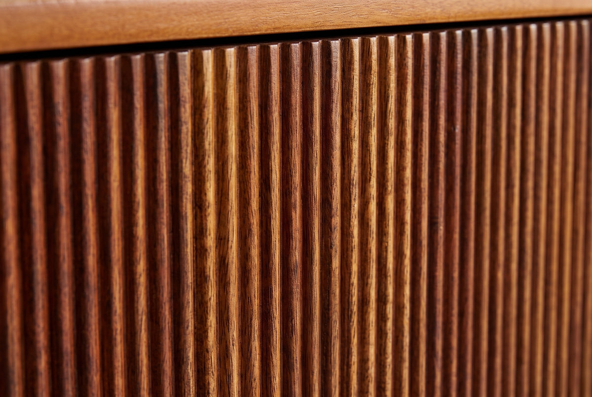 Close-up of the carved vertical reeds on the Teulada nightstand in solid mango with a winewood finish