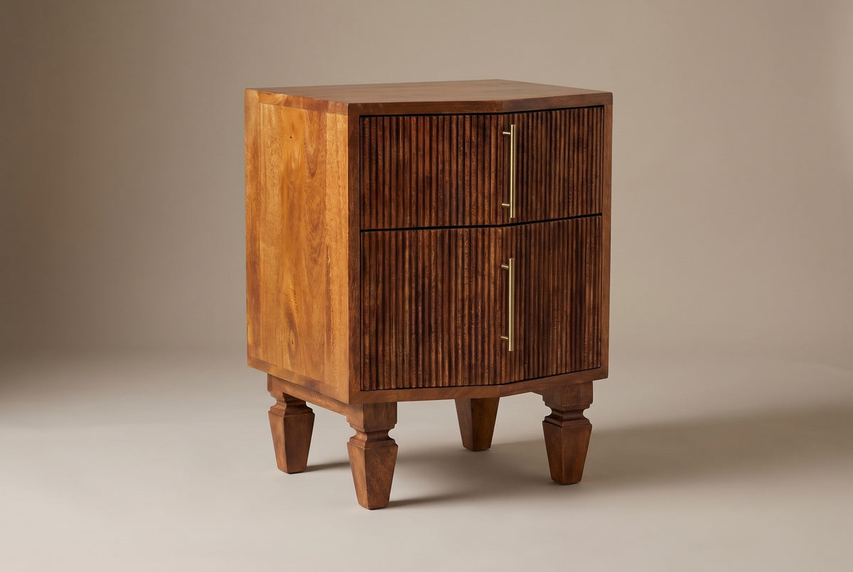The Teulada two-drawer nightstand in solid mango with a winewood finish and carved reeded drawer fronts, three-quarter view on a light studio backdrop