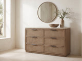 Thiene 66.5-Inch Toffee Oak Stone-Top 6-Drawer Dresser under a round bronze mirror in a villa bedroom