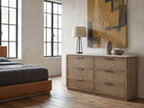 Thiene 66.5-Inch Toffee Oak Stone-Top 6-Drawer Dresser against a plaster wall in an industrial loft bedroom