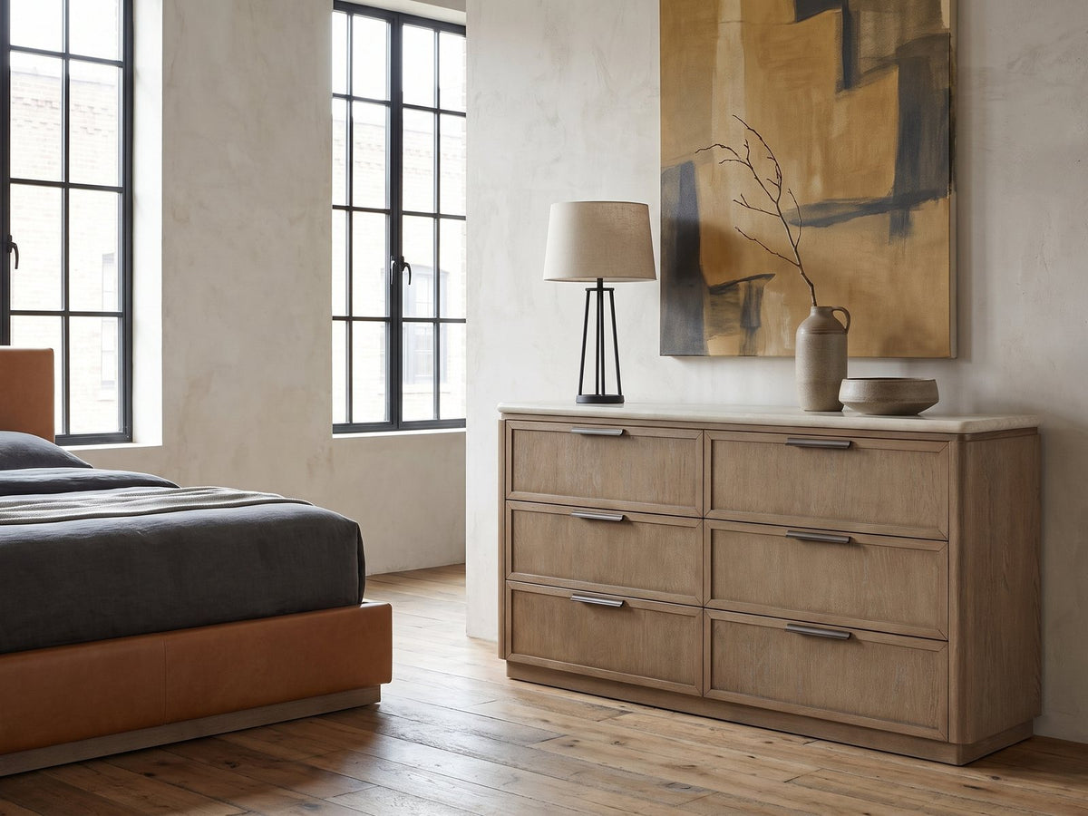 Thiene 66.5-Inch Toffee Oak Stone-Top 6-Drawer Dresser against a plaster wall in an industrial loft bedroom