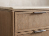 Close-up of the Thiene 66.5-Inch Toffee Oak Stone-Top 6-Drawer Dresser: the bronze pull on the mitred oak frame under the cream stone top