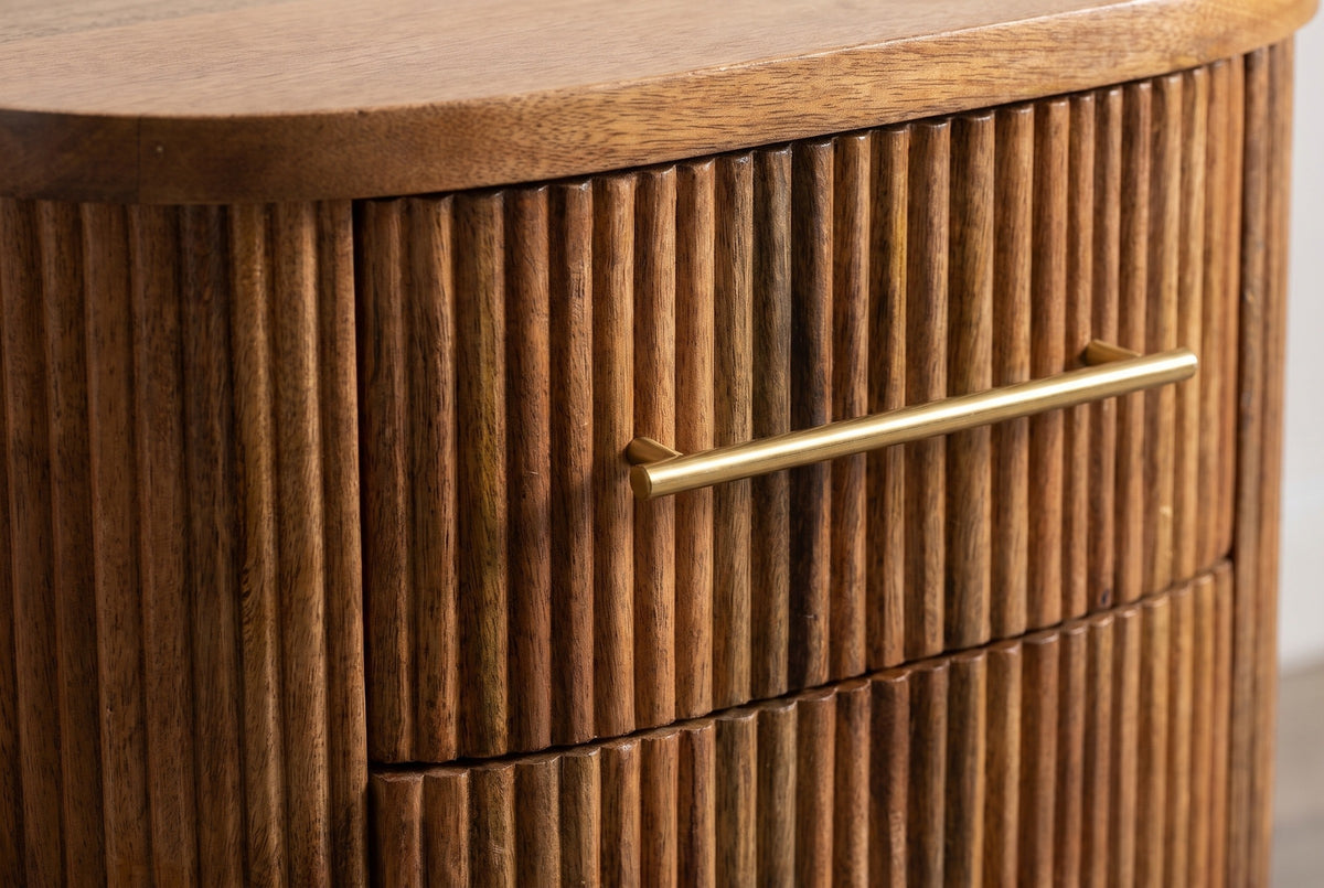 The upper drawer of the Thiesi nightstand: a slim brass bar pull on a reeded mango drawer front, under the flat top