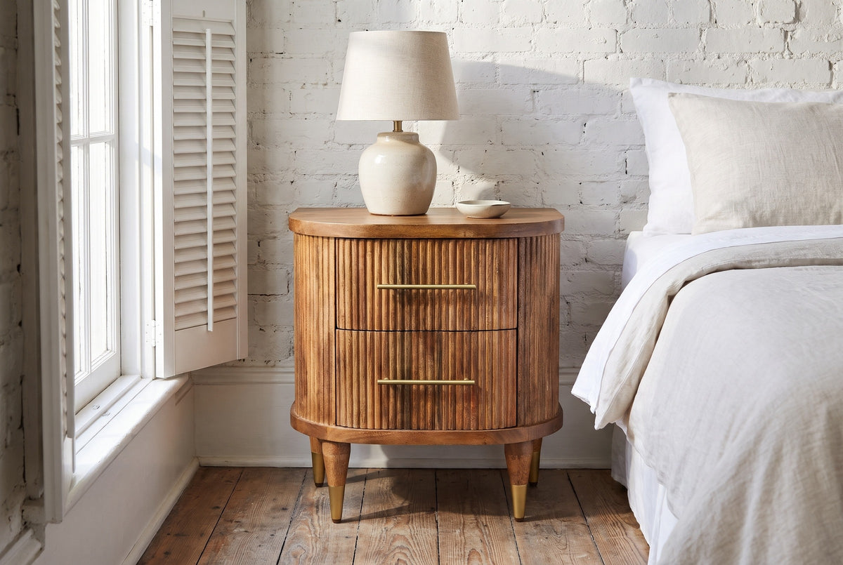 Thiesi reeded mango nightstand with a ceramic lamp against a whitewashed brick wall in a Savannah bedroom