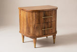 The Thiesi two-drawer nightstand in golden brown reeded mango wood with brass pulls, three-quarter view on a light studio backdrop