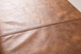 Close-up of the genuine leather on the Todi bench: warm antique tan with a mottled tone, fine natural grain and a stitched seam