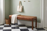 Todi antique tan leather bench in a Charleston entry hall with a sage-green plaster wall, a black-and-white checkerboard marble floor, a folded linen throw and a seagrass basket