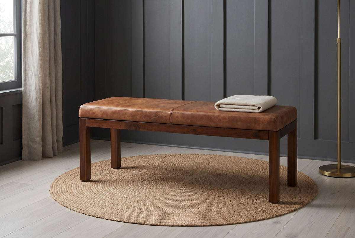 Todi antique tan leather bench against charcoal-grey board-and-batten panelling in a Portland reading room with a pale ash floor, a round jute rug and a folded cream throw