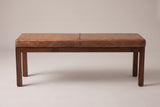 The Todi bench, front view on a light studio backdrop: one seam across the leather cushion, a slim wood apron and four straight square legs
