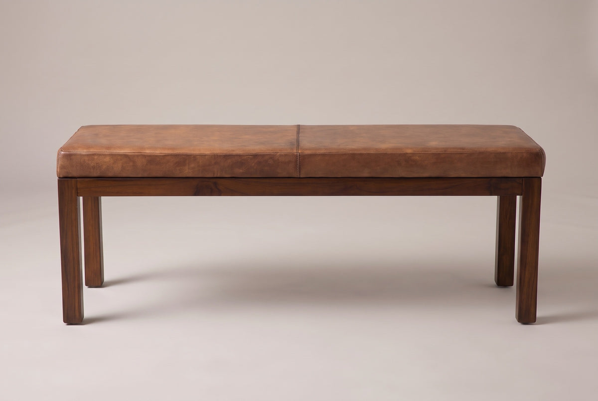 The Todi bench, front view on a light studio backdrop: one seam across the leather cushion, a slim wood apron and four straight square legs