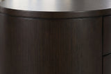 Close-up of the deep espresso eucalyptus veneer on the Tortoli nightstand: a fine straight grain under the thin edge of the oval top