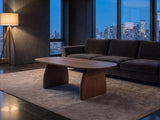 Tortona 47-Inch Oval Walnut-Finish Wood Veneer Coffee Table on a wool rug in front of a velvet sofa in a city penthouse at blue hour