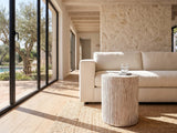 Tortora Carved Whitewash Drum Side Table beside a linen sofa in a poolside villa