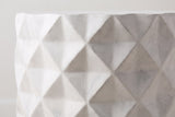 Close-up of the antique white lightweight concrete on the Tortorici side table: shallow diamond facets with a faint grey wash and fine pores