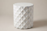 The Tortorici antique white faceted concrete drum side table, three-quarter view on a light studio backdrop