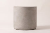 The Trabia side table seen straight from the side: a light grey concrete cylinder with straight sides and a softly rounded foot
