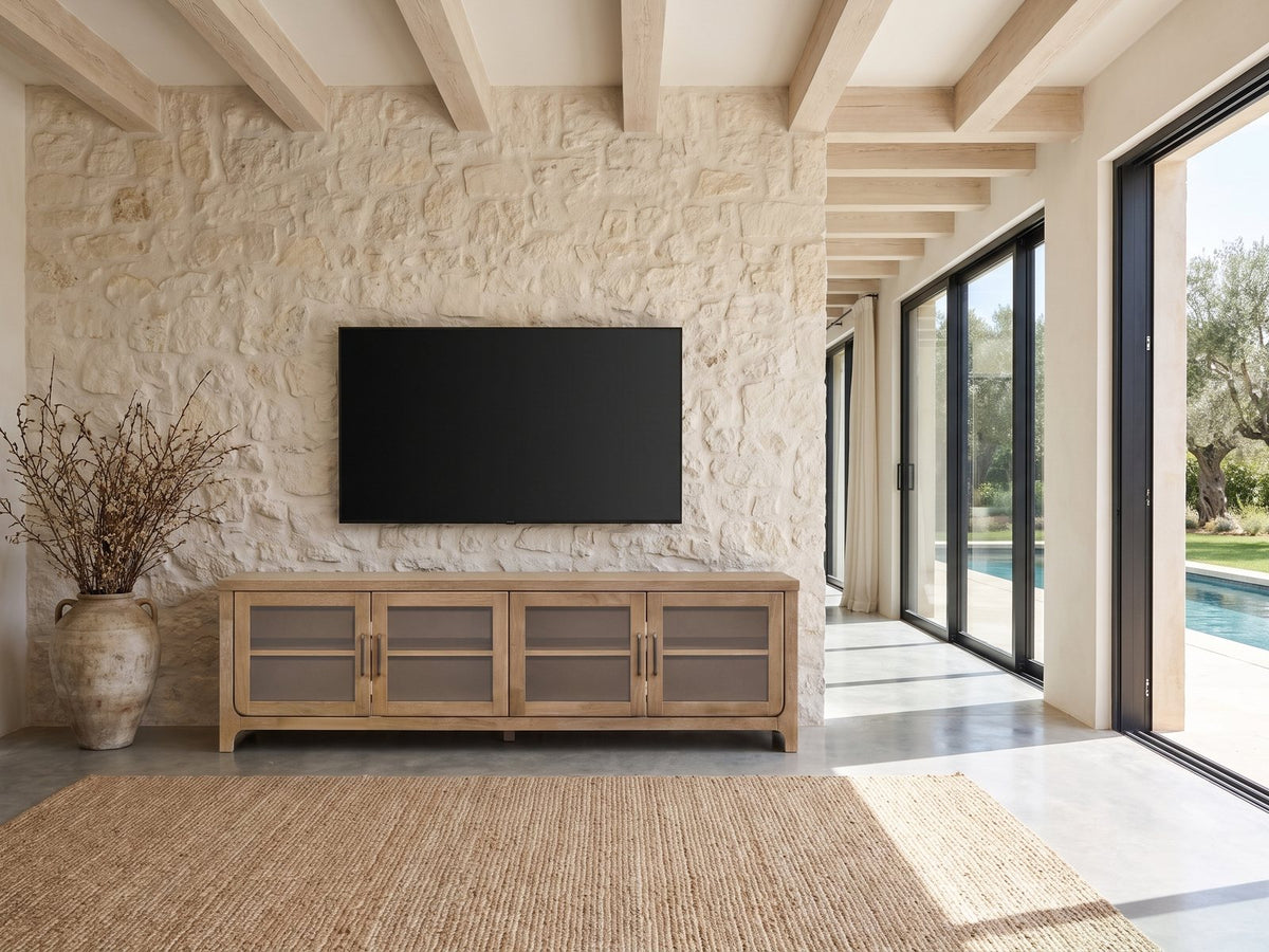 Tremezzo Washed Oak Media Console under a wall-mounted screen on a pale stone wall in a poolside villa