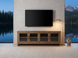 Tremezzo Washed Oak Media Console under a wall-mounted screen in a mountain lake house at dusk