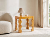 Tricarico Burl Veneer Scalloped Side Table with a lamp and a ceramic bowl beside a cream boucle armchair in a bright plaster room