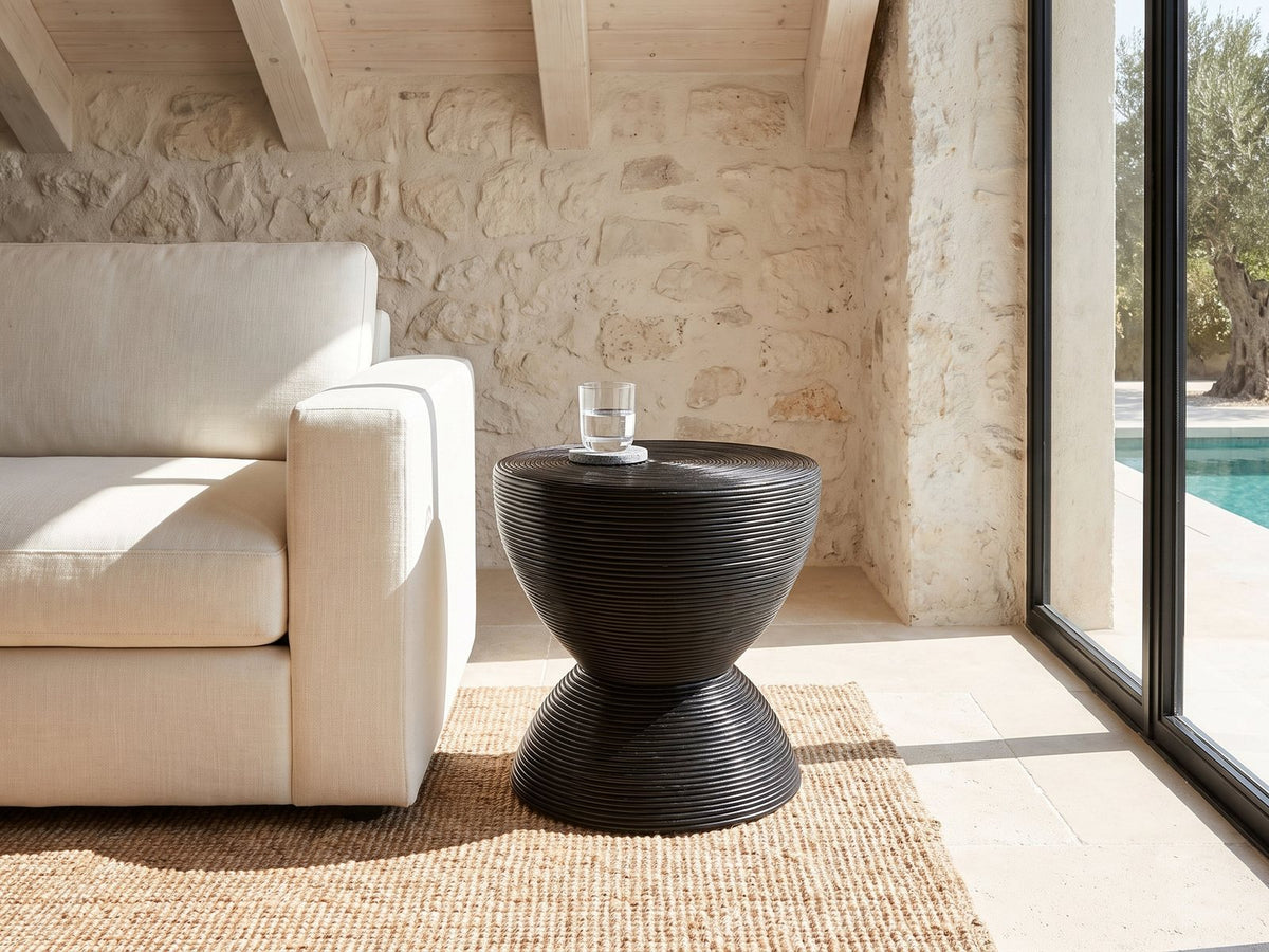 Tricase Black Rattan Hourglass Side Table beside a linen sofa in a poolside villa