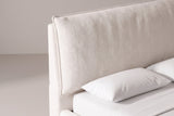 The upper corner of the Trivento headboard: the oversized pillow cushion with its flat flange edge tilted against the plain upholstered panel, above a white pillow