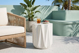 Troina concrete side table on pale terrazzo in a Miami Beach courtyard with a seafoam-green stucco wall, a bird of paradise and palms, beside a rope lounge chair (chair and decor not included)