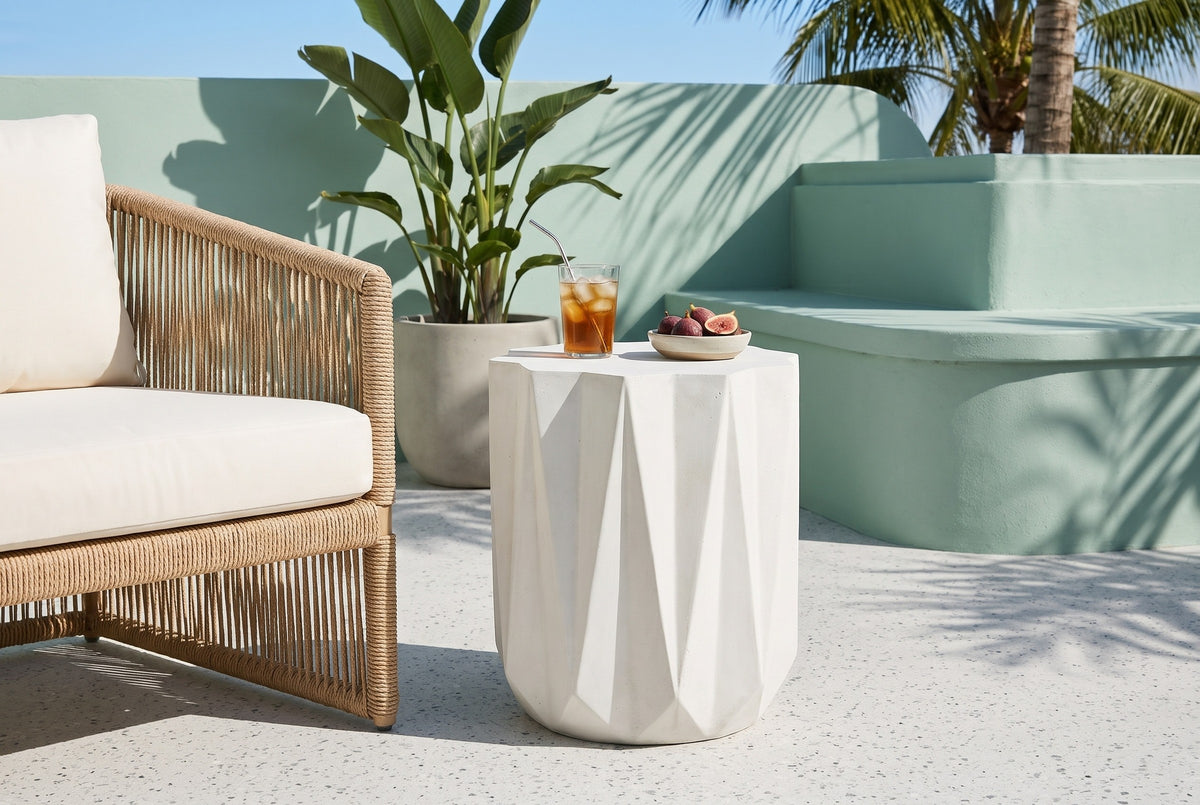 Troina concrete side table on pale terrazzo in a Miami Beach courtyard with a seafoam-green stucco wall, a bird of paradise and palms, beside a rope lounge chair (chair and decor not included)