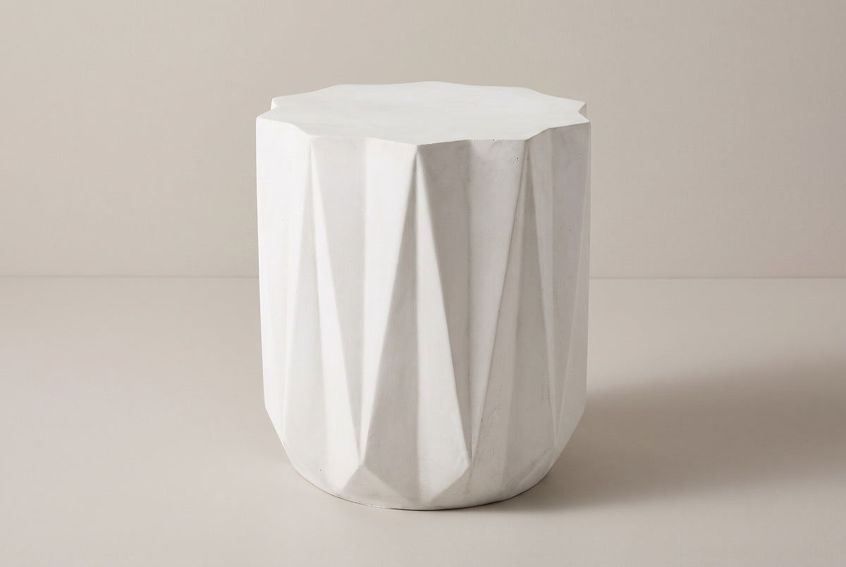 The Troina antique white faceted concrete side table, three-quarter view on a light studio backdrop