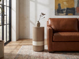 Tuglie Cerused Toffee Drum Side Table beside a leather sofa in an industrial loft