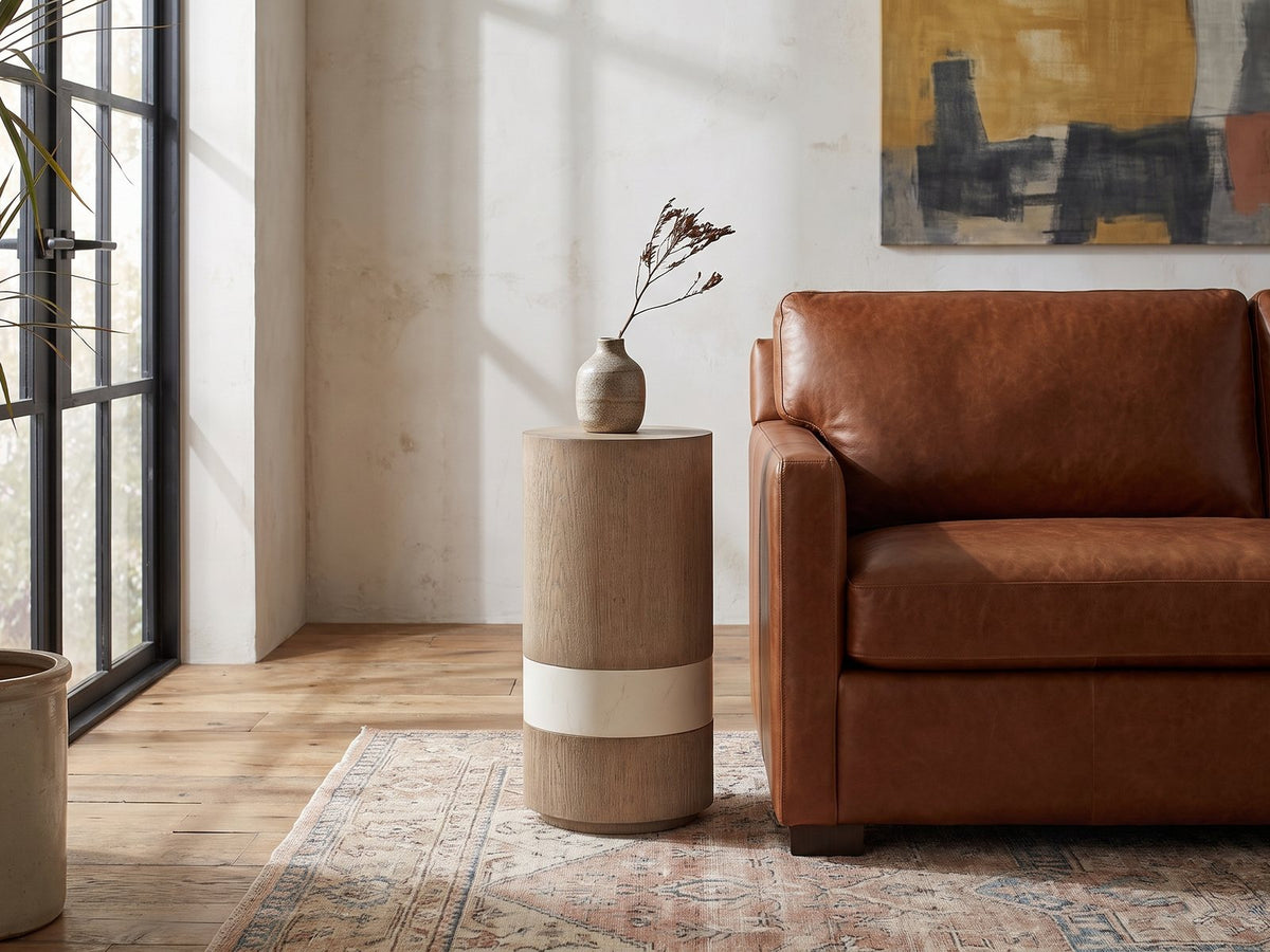 Tuglie Cerused Toffee Drum Side Table beside a leather sofa in an industrial loft