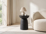 Tursi Black Mango Ribbed Pedestal Side Table with a lamp and a ceramic bowl beside a cream boucle armchair in a bright plaster room