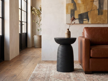 Tursi Black Mango Ribbed Pedestal Side Table beside a leather sofa in an industrial loft