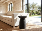 Tursi Black Mango Ribbed Pedestal Side Table beside a linen sofa in a poolside villa